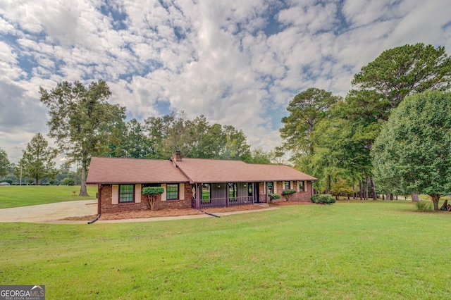 ranch-style home with brick siding, covered porch, and a front yard