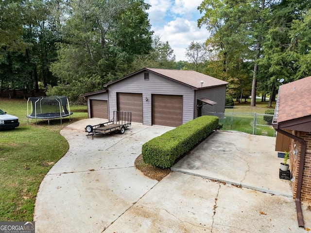 detached garage with a trampoline and fence