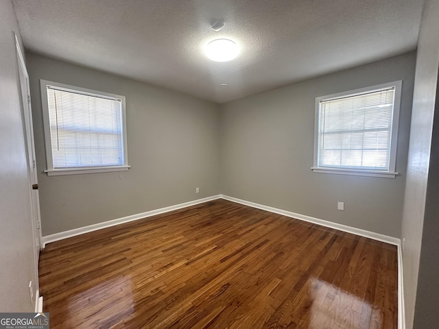 unfurnished room featuring dark hardwood / wood-style floors and a textured ceiling