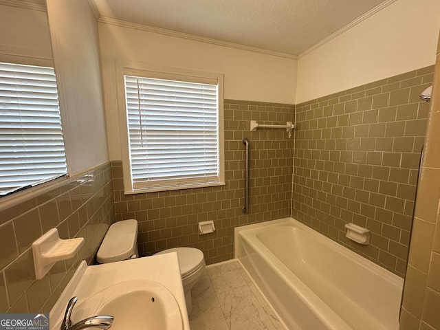 bathroom featuring crown molding, toilet, and tile walls