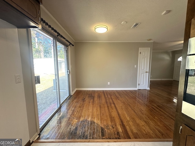 unfurnished room featuring dark wood-type flooring, ornamental molding, and a textured ceiling