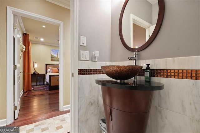 bathroom with crown molding, vanity, hardwood / wood-style floors, and tile walls