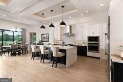 kitchen featuring white cabinetry, a center island, decorative light fixtures, oven, and wall chimney exhaust hood