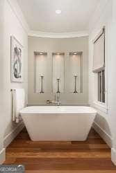 bathroom featuring wood-type flooring, ornamental molding, and a bath