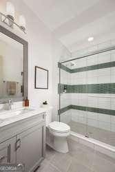 bathroom with tiled shower, vanity, toilet, and tile patterned floors