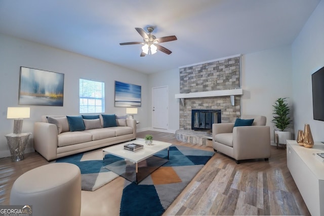 living room with wood-type flooring, ceiling fan, and a fireplace