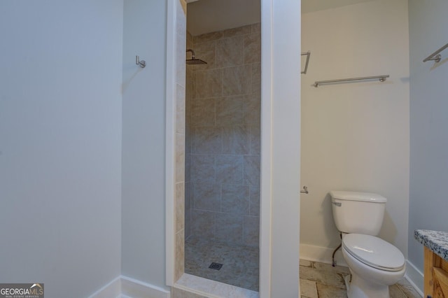 bathroom with tiled shower, vanity, and toilet