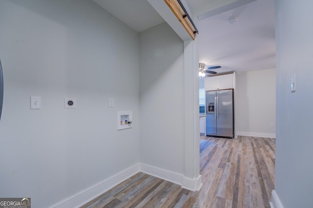 laundry room with hookup for an electric dryer, washer hookup, a barn door, and light wood-type flooring