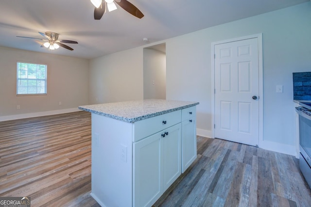 kitchen with ceiling fan, light wood-type flooring, a kitchen island, and white cabinets