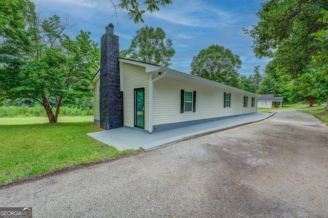 view of side of property with a patio and a lawn