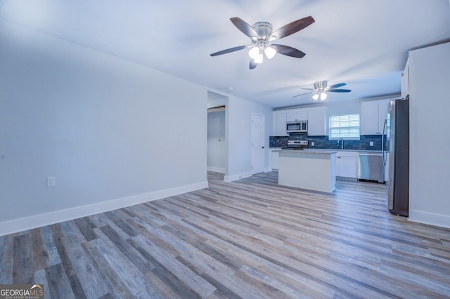 kitchen featuring white cabinetry, tasteful backsplash, light hardwood / wood-style flooring, appliances with stainless steel finishes, and a kitchen island