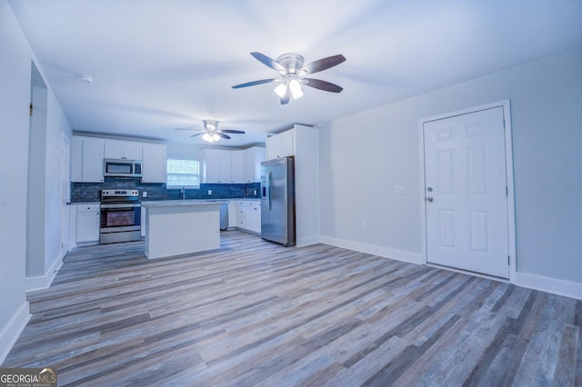 kitchen featuring white cabinetry, stainless steel appliances, light hardwood / wood-style floors, and a kitchen island