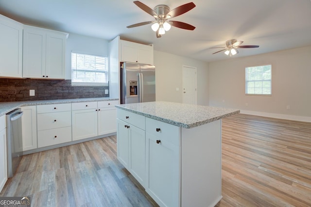 kitchen with white cabinetry, appliances with stainless steel finishes, a center island, and plenty of natural light