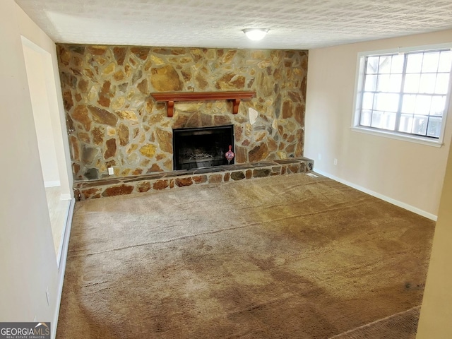 unfurnished living room with carpet flooring, a stone fireplace, and a textured ceiling