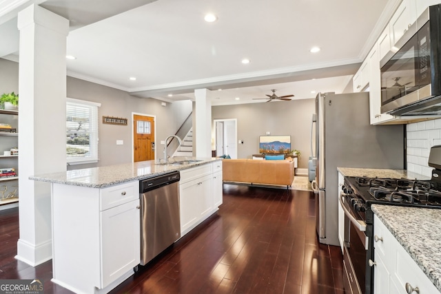 kitchen with stainless steel appliances, sink, white cabinets, and light stone counters