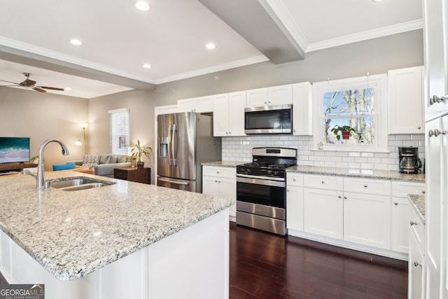 kitchen with white cabinetry, sink, stainless steel appliances, and a center island with sink