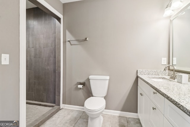 bathroom featuring vanity, a tile shower, tile patterned floors, and toilet