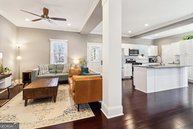 living room featuring beamed ceiling, ornamental molding, dark hardwood / wood-style floors, and ceiling fan