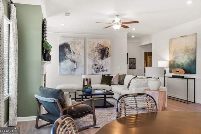 living room featuring ceiling fan, ornamental molding, and light hardwood / wood-style floors