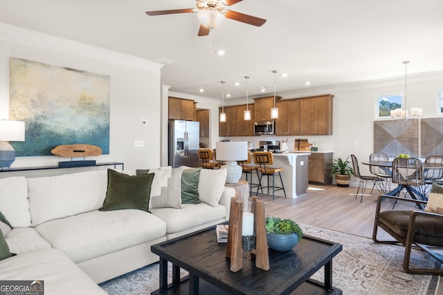 living room featuring crown molding, ceiling fan with notable chandelier, and light hardwood / wood-style flooring