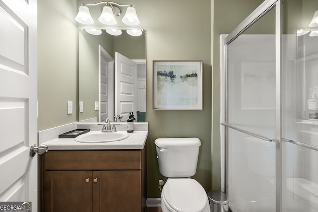 bathroom featuring vanity, a shower with shower door, and toilet