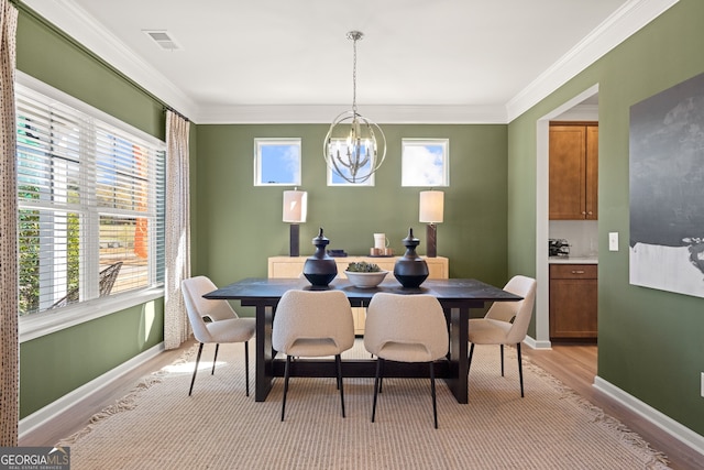 dining space featuring ornamental molding, light wood-type flooring, and an inviting chandelier