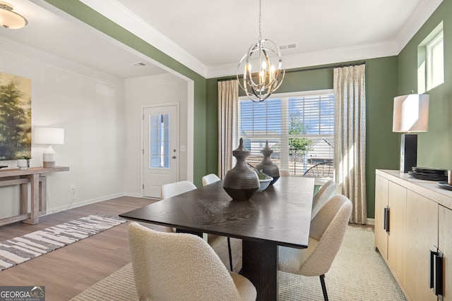 dining room with ornamental molding, light hardwood / wood-style flooring, and a notable chandelier