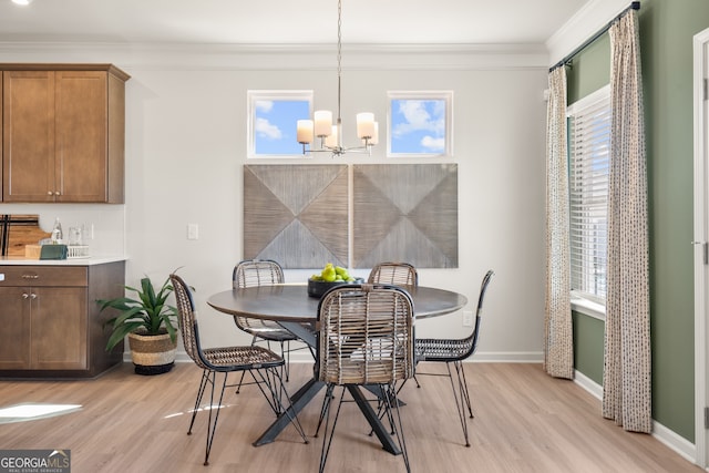 dining space featuring ornamental molding, a chandelier, and light hardwood / wood-style flooring