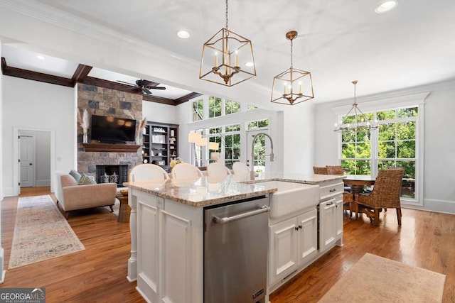 kitchen featuring pendant lighting, sink, dishwasher, and a center island with sink