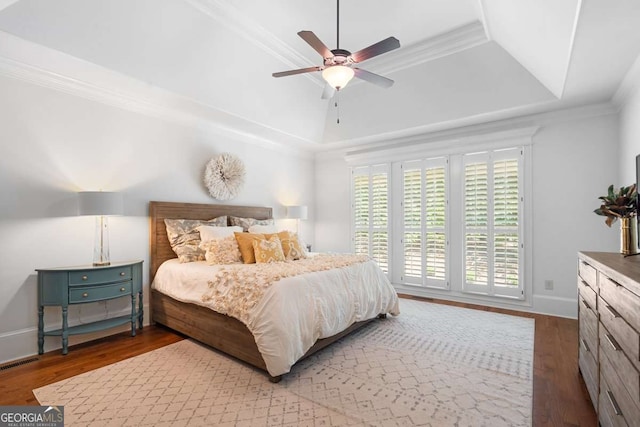 bedroom with wood-type flooring, ornamental molding, ceiling fan, and a tray ceiling