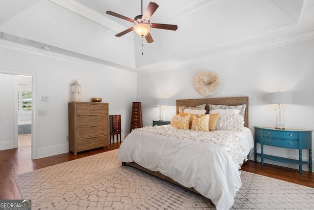 bedroom featuring dark wood-type flooring, ornamental molding, a raised ceiling, and ceiling fan