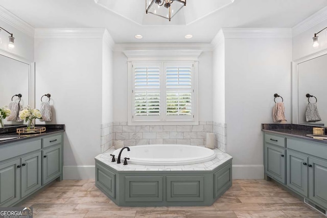 bathroom with ornamental molding, a bathing tub, and vanity