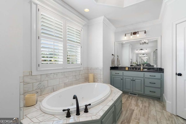 bathroom with hardwood / wood-style floors, ornamental molding, tiled bath, and vanity