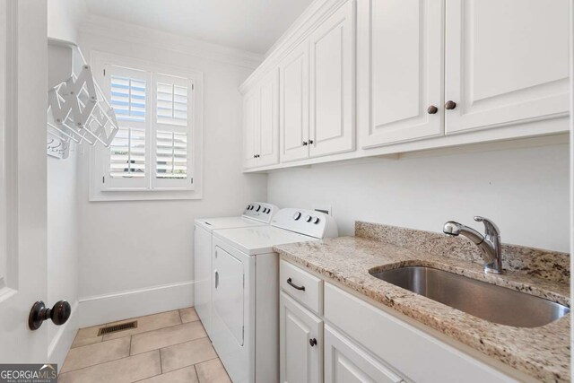 washroom featuring sink, cabinets, light tile patterned floors, ornamental molding, and washer and clothes dryer