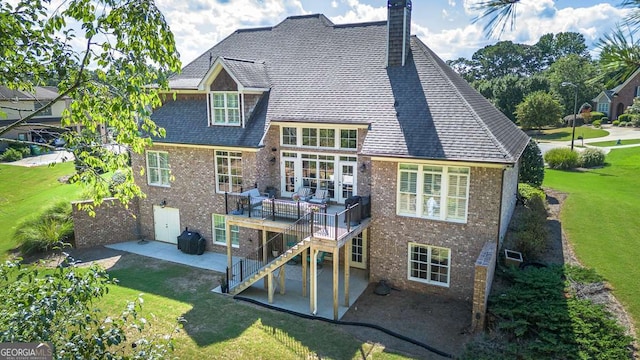 rear view of property with a lawn, a deck, and a patio area