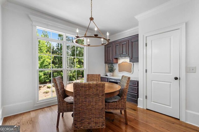 dining space with ornamental molding, a chandelier, and light wood-type flooring