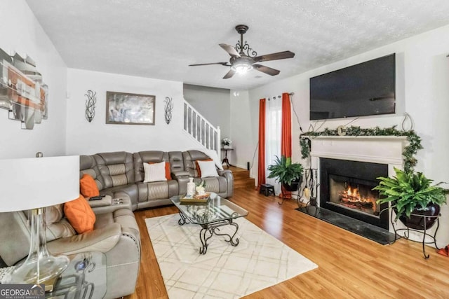 living room featuring wood-type flooring, a textured ceiling, and ceiling fan