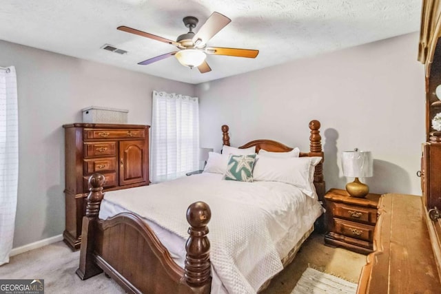 bedroom featuring a textured ceiling, light colored carpet, and ceiling fan