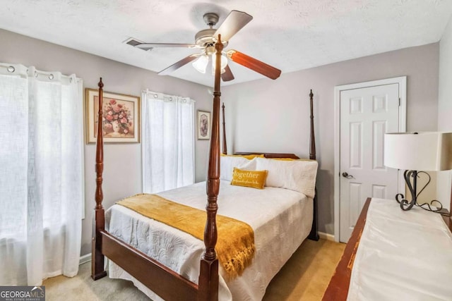 carpeted bedroom featuring ceiling fan and a textured ceiling