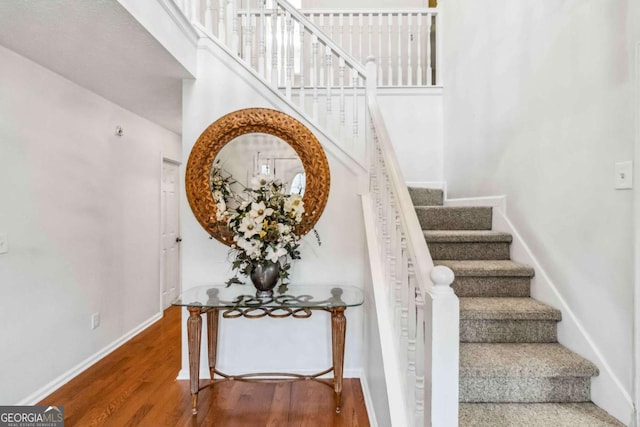 stairway featuring a towering ceiling and hardwood / wood-style floors