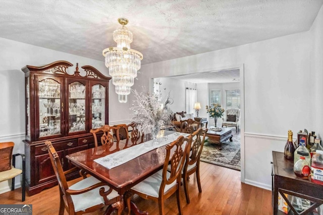 dining room with an inviting chandelier, hardwood / wood-style floors, and a textured ceiling