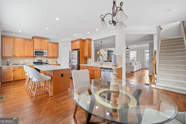 dining area featuring stairway, ornamental molding, wood finished floors, ceiling fan with notable chandelier, and recessed lighting