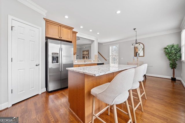 kitchen with crown molding, dark wood-style floors, a kitchen island, and stainless steel fridge with ice dispenser