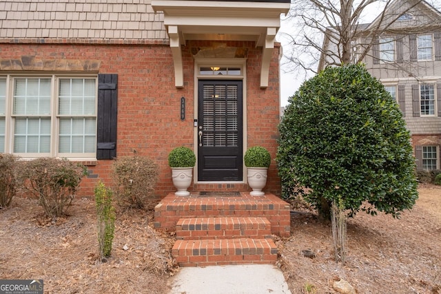 doorway to property with brick siding and mansard roof