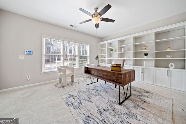 office area with ceiling fan, visible vents, baseboards, and light colored carpet