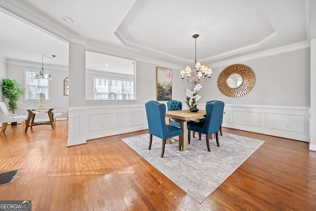 dining space featuring a chandelier, light wood finished floors, visible vents, and crown molding