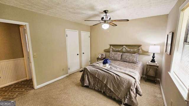 carpeted bedroom featuring ceiling fan and a textured ceiling