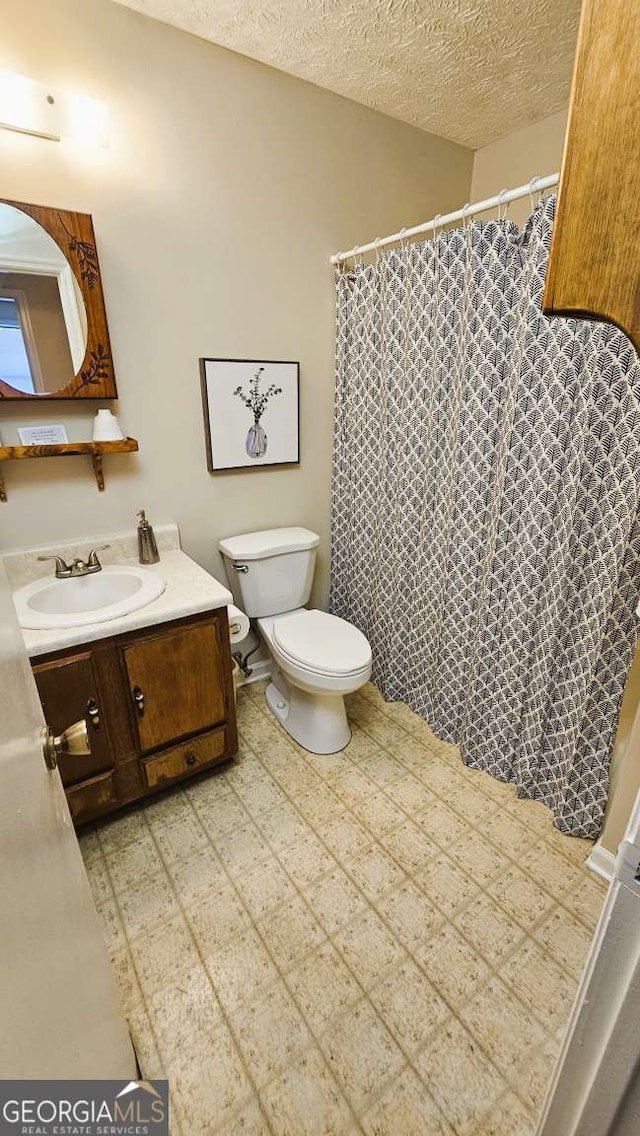 bathroom with vanity, a textured ceiling, and toilet