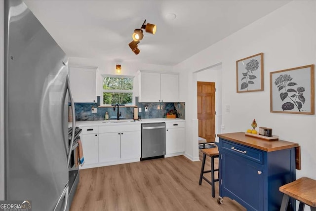 kitchen featuring appliances with stainless steel finishes, blue cabinets, tasteful backsplash, sink, and white cabinets