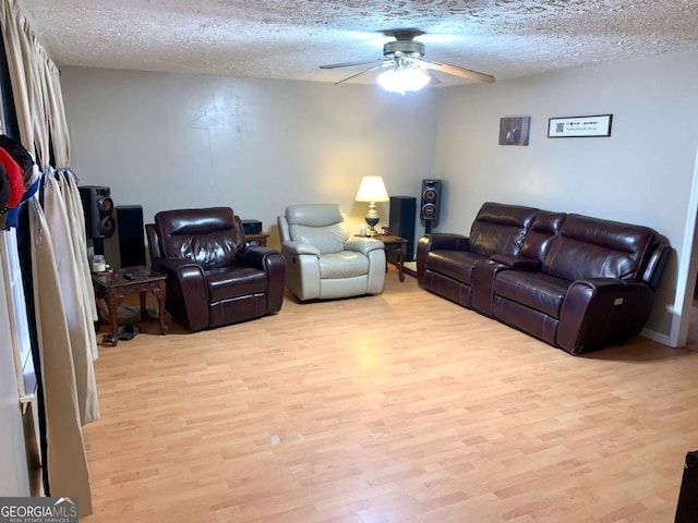 living room with ceiling fan, a textured ceiling, and light wood-type flooring